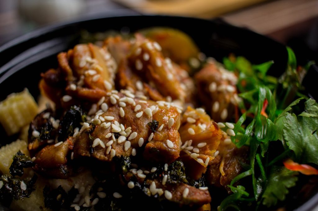 A savory Asian dish garnished with sesame seeds and fresh greens, perfectly captured in a close-up shot.