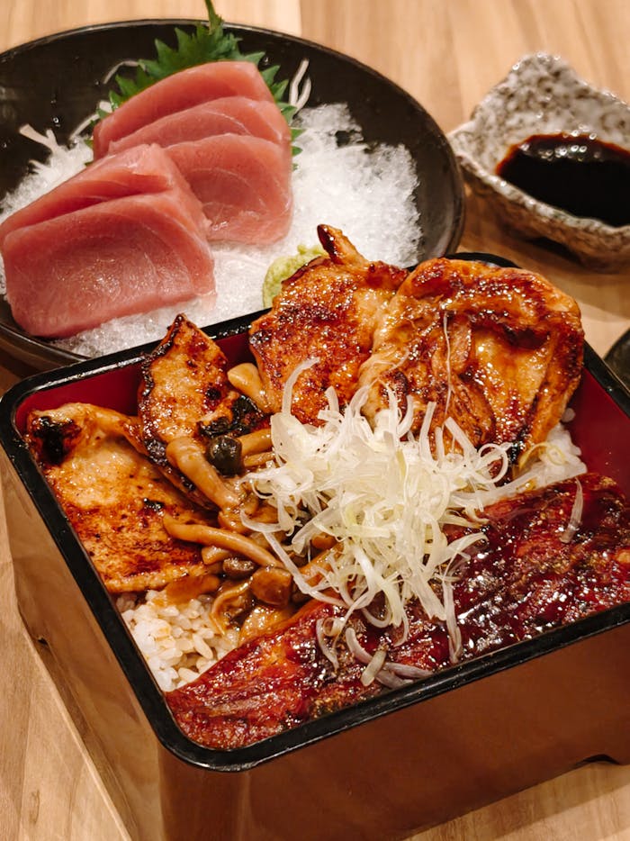 Mouth-watering Japanese meal featuring fresh sashimi and grilled chicken rice bowl.