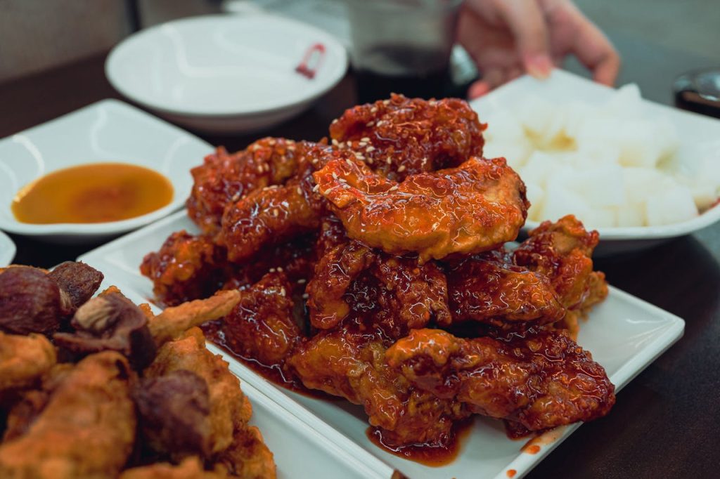 Close-up of spicy Korean fried chicken with accompaniments on a dining table in Suwon-si, South Korea.