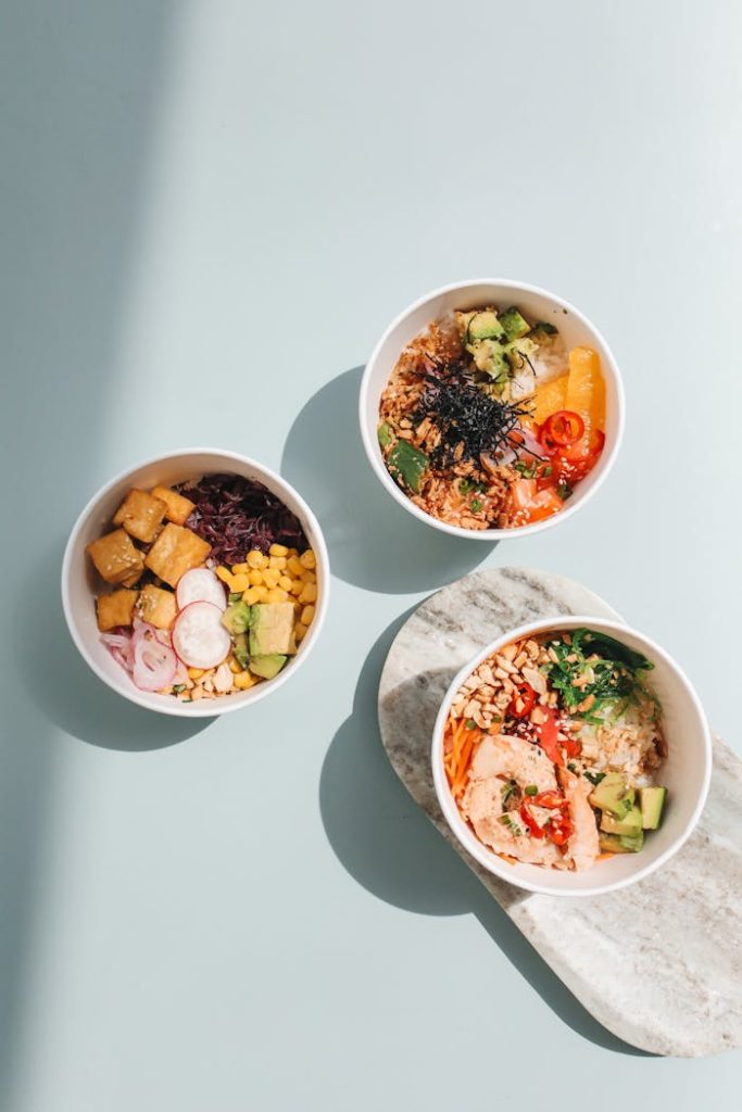 Three colorful Hawaiian poke bowls with fresh ingredients in bright lighting.