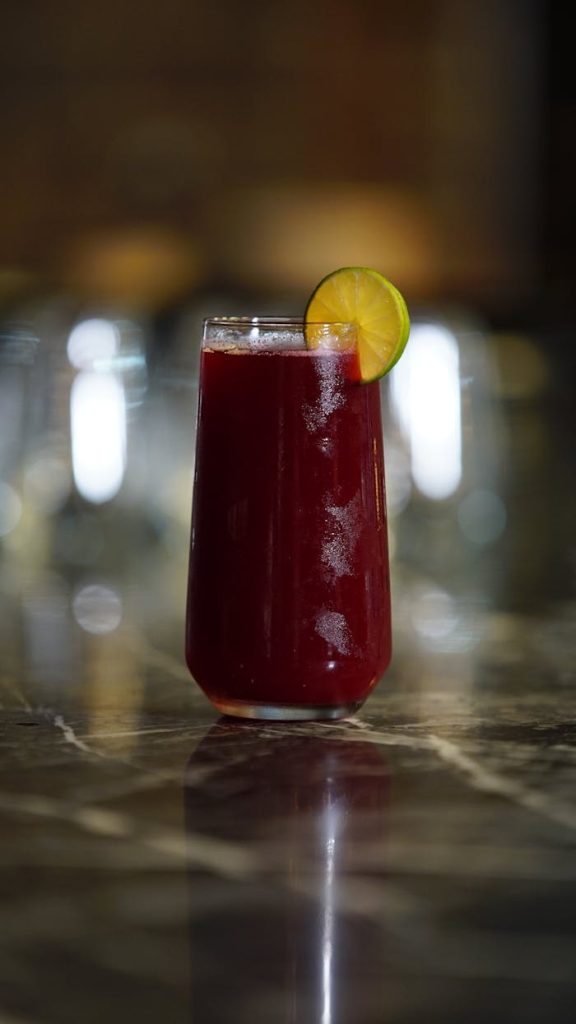 Chilled hibiscus beverage in a glass with a lime slice, perfect for summer refreshment.