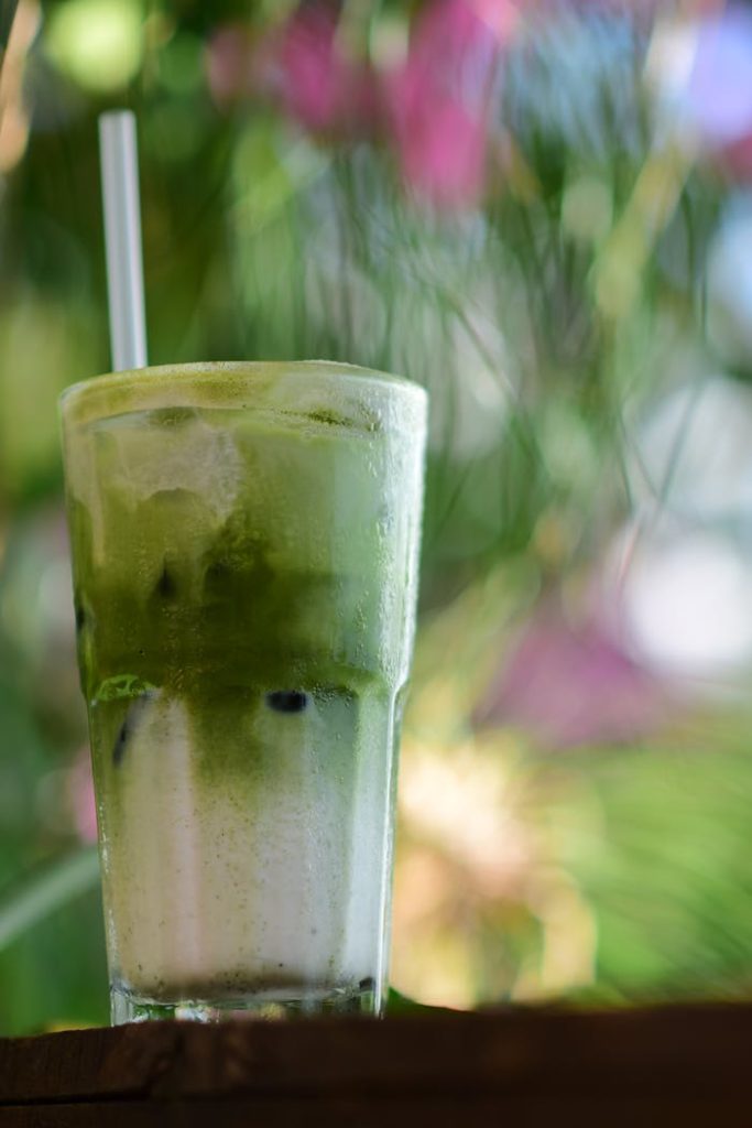 A chilled glass of iced matcha latte with milk, perfect for a refreshing beverage on a sunny day.