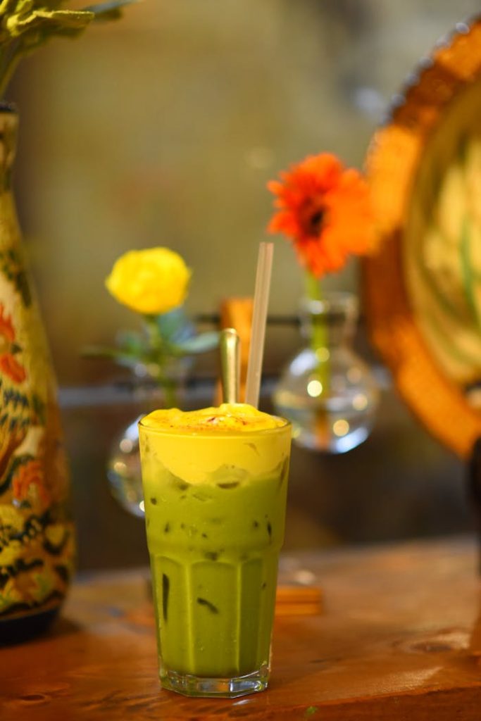 Colorful iced matcha latte with bright flowers in a cozy indoor setting.
